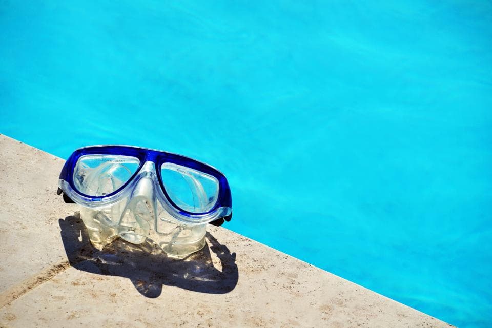 O pereche de ochelari de înot așezată pe marginea unei piscine. (Foto ilustrativă: Maarten van den Heuvel / CC0 1.0, Openverse)