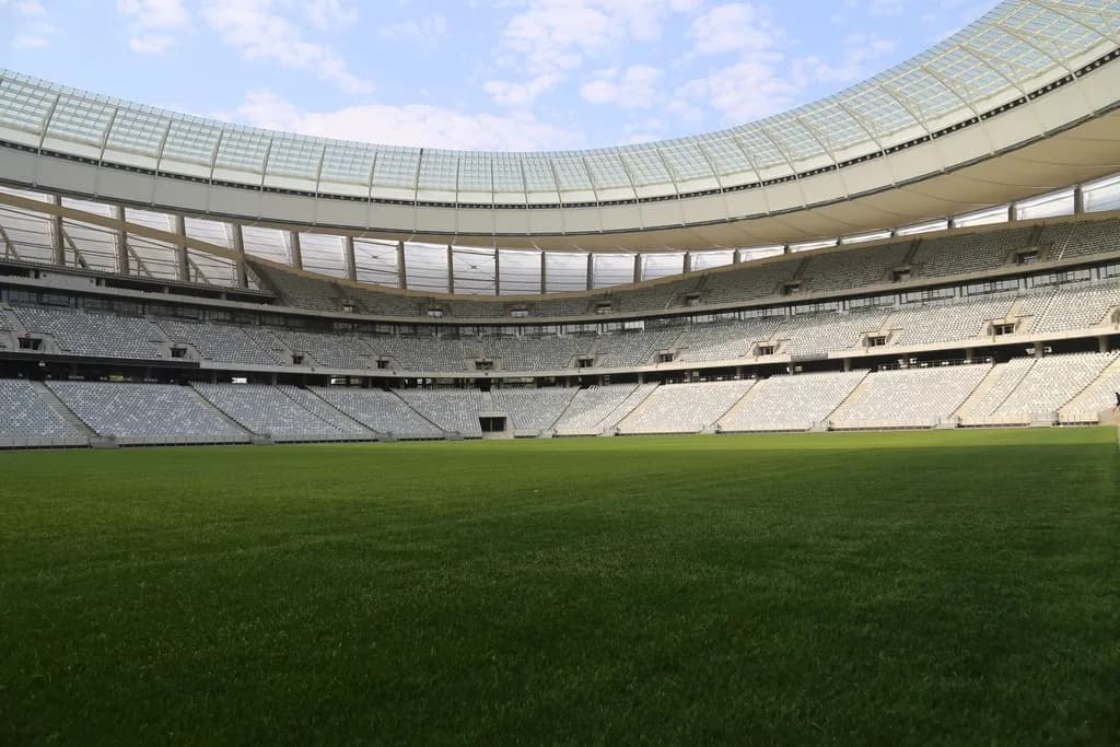 Un stadion de fotbal modern, văzut din interior, cu terenul și tribunele goale. (Foto ilustrativă: necunoscut / CC0 1.0, Openverse)