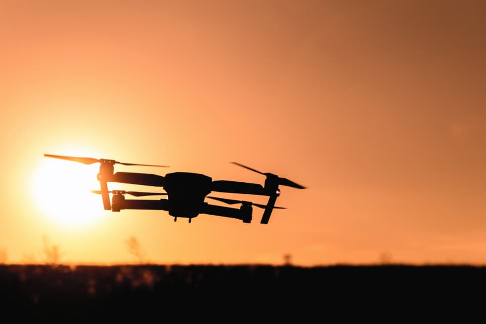 O dronă quadcopter surprinsă în zbor, în siluetă, pe fundalul unui apus. (Foto ilustrativă: JESHOOTS.com / CC0 1.0, Openverse)