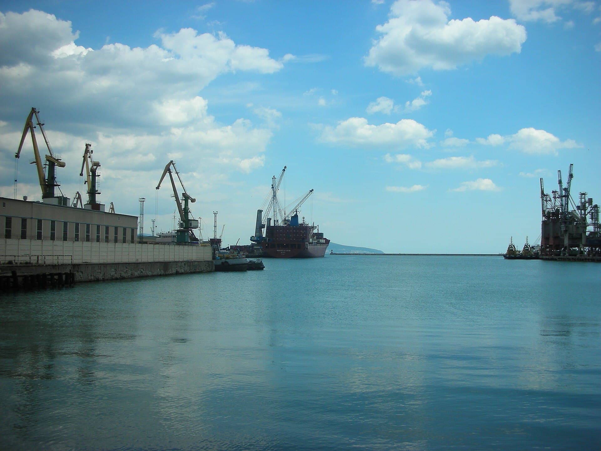 Un port maritim cu nave comerciale și macarale de încărcare, fotografiat de pe apă. (Foto: bibikoff / Public domain, Wikimedia Commons)