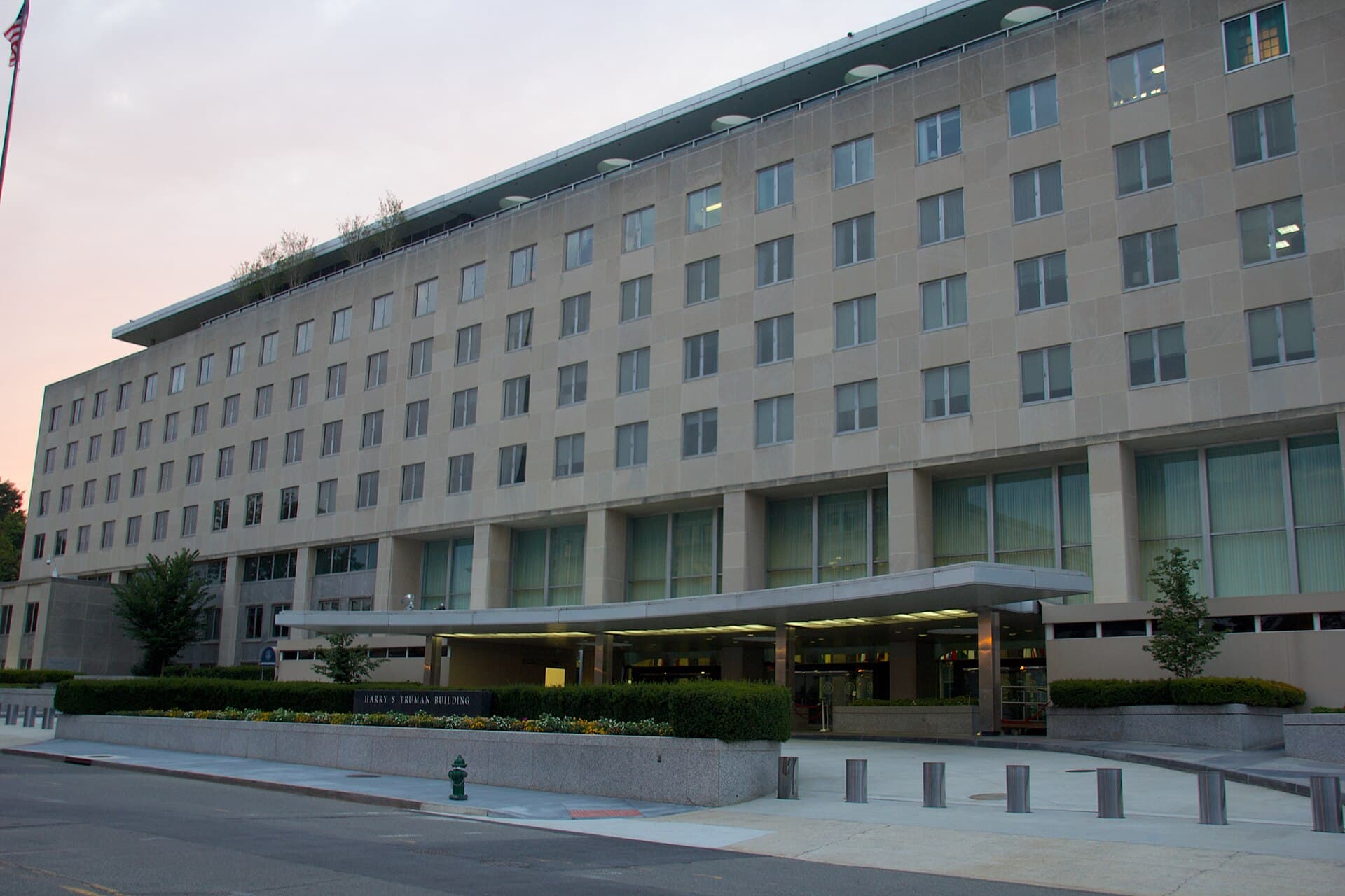 O clădire instituțională mare, cu un steag american și o intrare principală, aparent sediul unei ambasade sau instituții diplomatice a SUA. (Foto: Photograph by Mike Peel ( www.mikepeel.net ). / CC BY-SA 4.0, Wikimedia Commons)