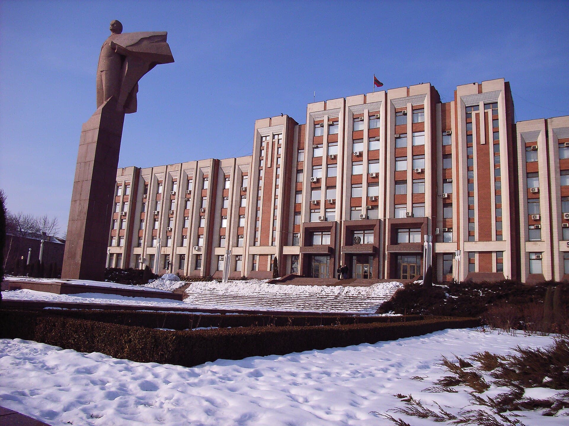 O clădire guvernamentală din Transnistria, cu un monument în față și steagul regiunii. (Foto: inyucho from Holland / CC BY 2.0, Wikimedia Commons)