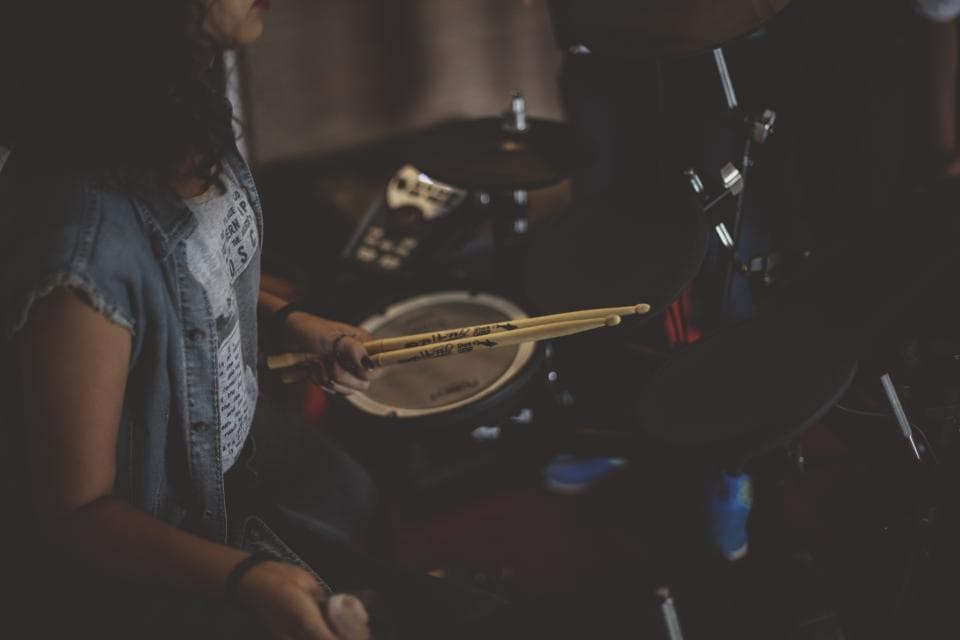 O persoană cântând la tobe într-un cadru întunecat, cu echipament de percuție. (Foto ilustrativă: Jo%E3o%20Silas / CC0 1.0, Openverse)