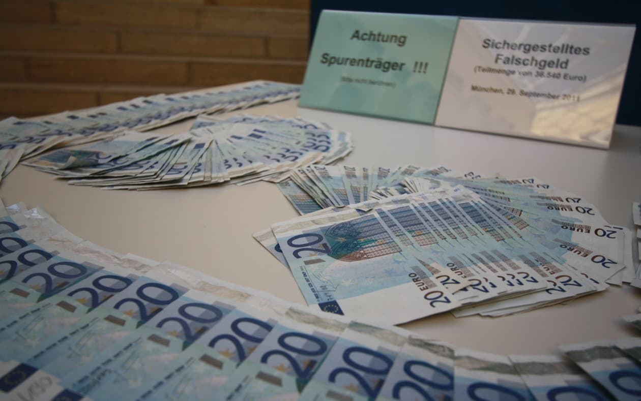 Bancnote euro de 20 și 50 de euro, așezate pe o masă, alături de două cartonașe cu text în limba germană. (Foto de arhivă: Michael Lucan / CC BY-SA 3.0 de, Wikimedia Commons)