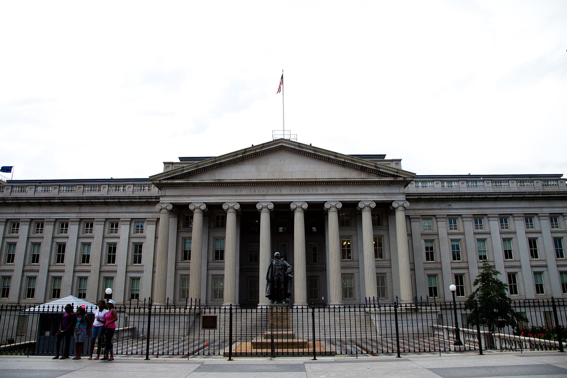 Se vede clădirea Departamentului Trezoreriei SUA, cu fațadă neoclasică, coloane și steagul american. (Foto: Almonroth / CC BY-SA 3.0, Wikimedia Commons)