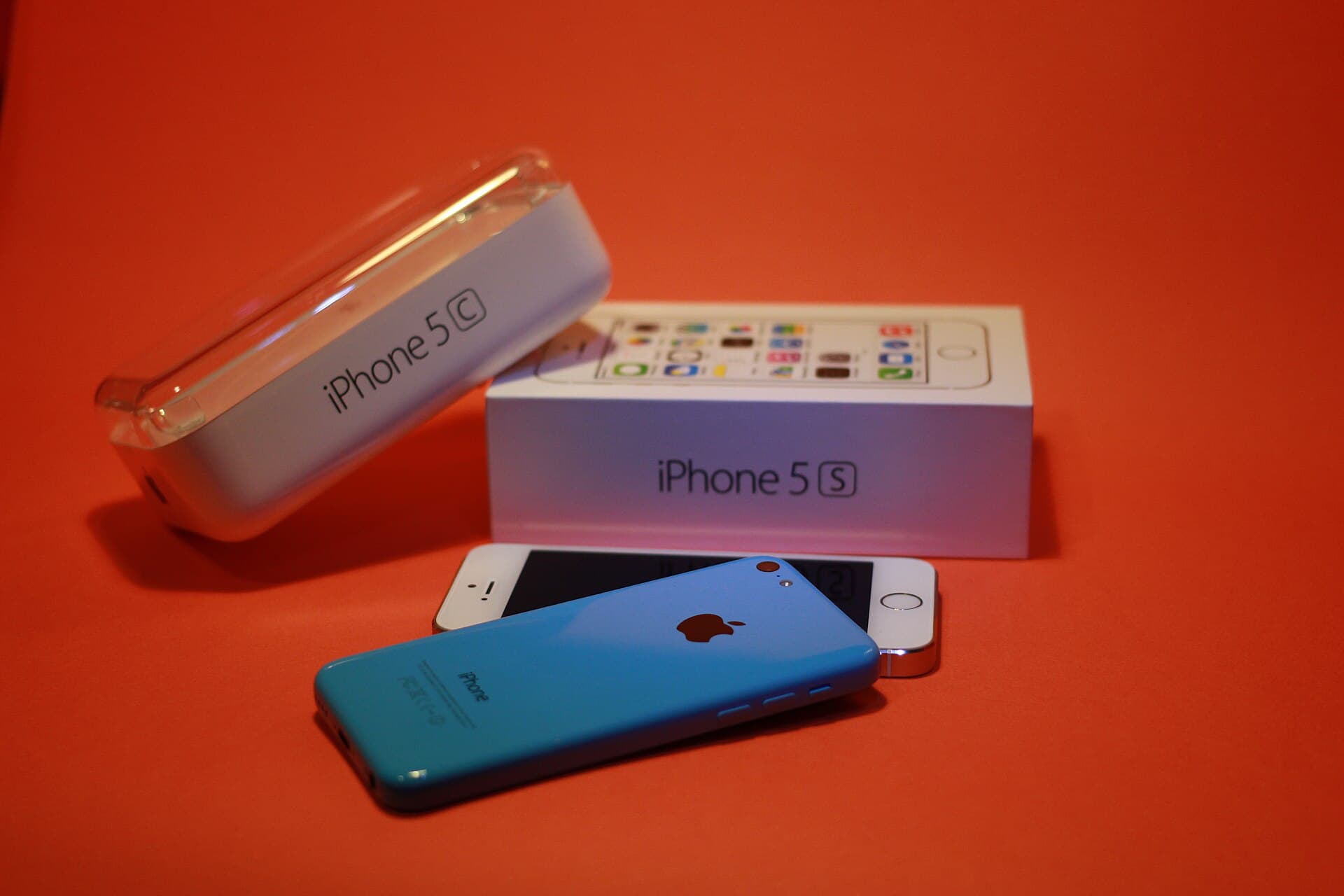 Telefoane Apple iPhone 5C și ambalajul lor, fotografiate pe un fundal roșu. (Foto: Maurizio Pesce from Milan, Italia / CC BY 2.0, Wikimedia Commons)