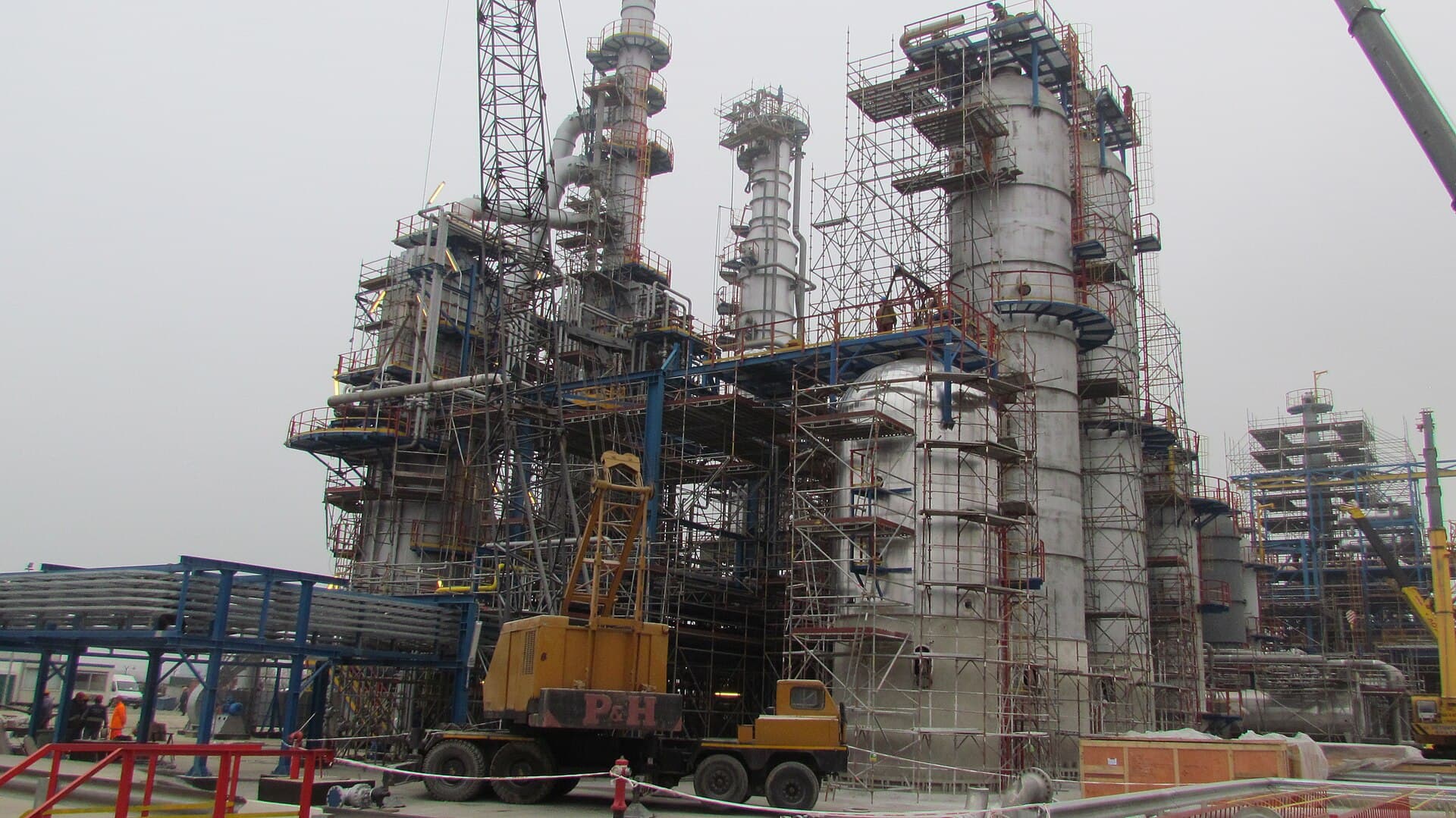 O instalație industrială de rafinare petrochimică, cu coloane și structuri metalice aflate în construcție. (Foto: Yakov Fedorov / CC BY-SA 3.0, Wikimedia Commons)