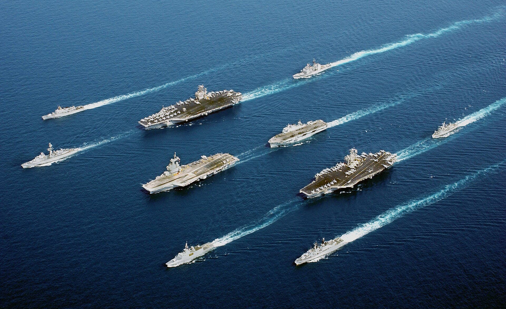 O formație navală cu două portavioane și mai multe nave militare navigând în larg. (Foto de arhivă: U.S. Navy/PH3 Alta I. Cutler / Public domain, Wikimedia Commons)
