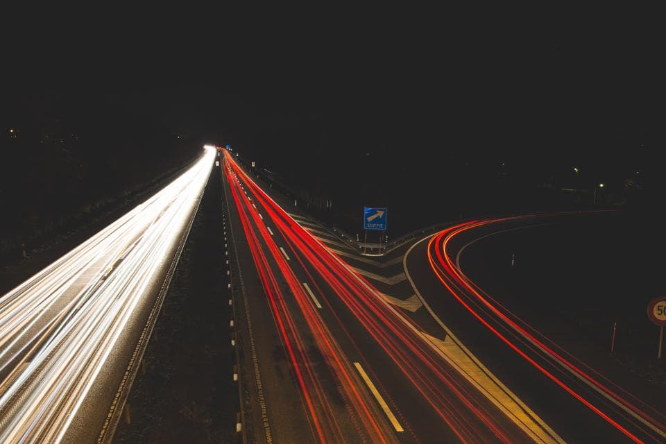 Șosea cu mai multe benzi, fotografiată noaptea prin expunere lungă, cu trasee luminoase ale mașinilor și o bretea de ieșire. (Foto ilustrativă: Negative Space / CC0 1.0, Openverse)