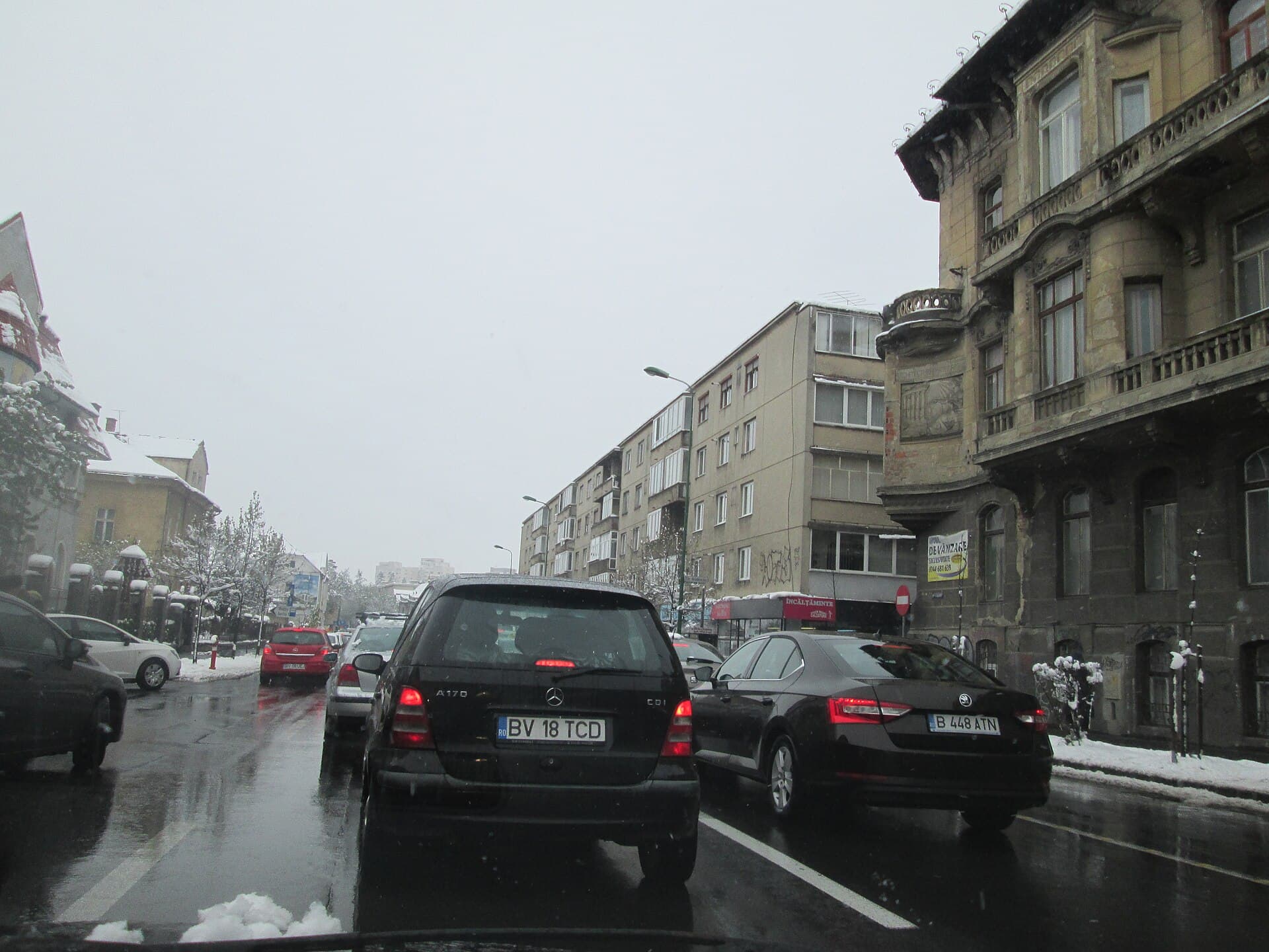 O stradă urbană aglomerată din România, cu mașini blocate în trafic pe carosabil umed și înzăpezit. (Foto: TrainSimFan / CC BY-SA 4.0, Wikimedia Commons)