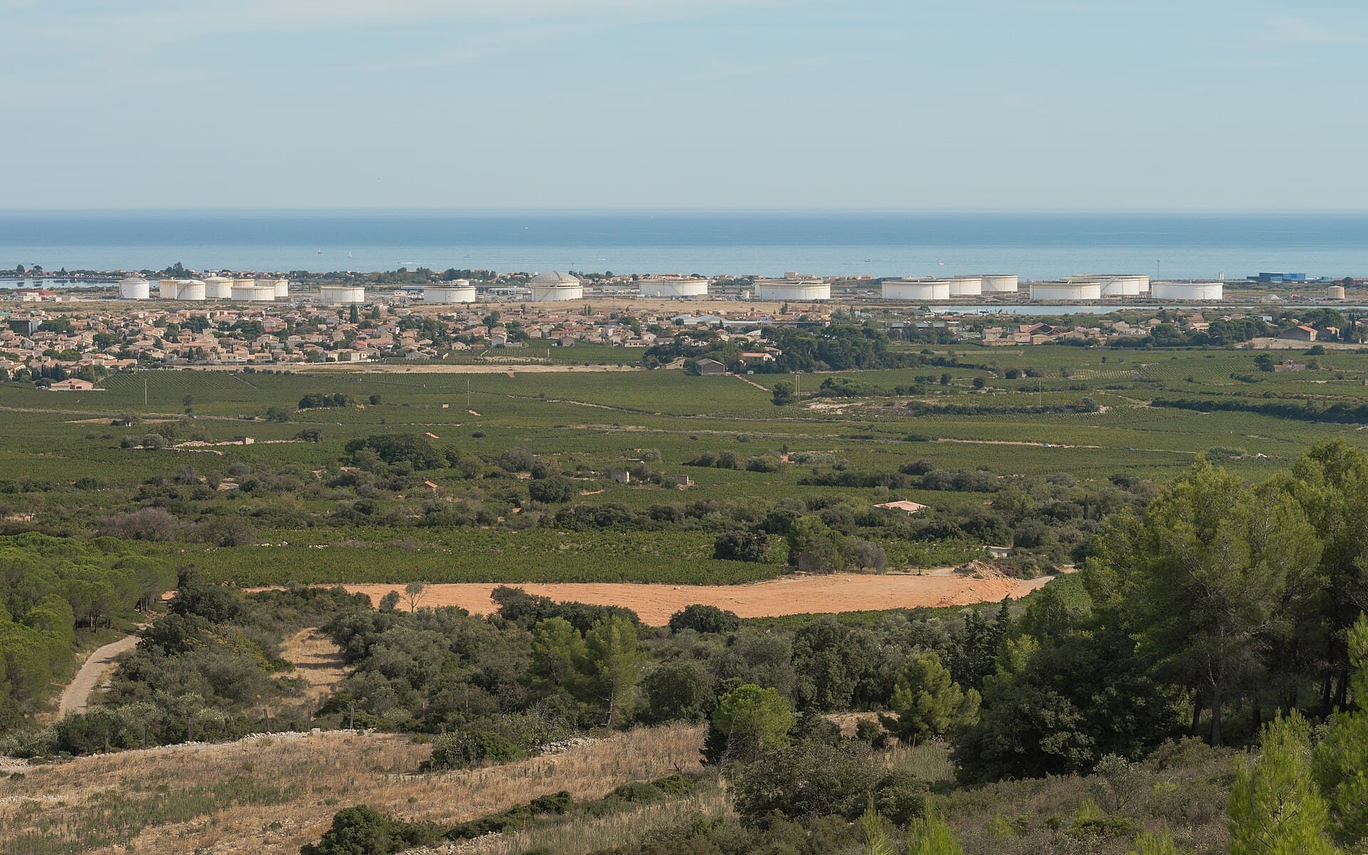 Peisaj industrial cu rezervoare mari de stocare a petrolului, văzute de la distanță. (Foto de arhivă: Christian Ferrer / CC BY-SA 3.0, Wikimedia Commons)