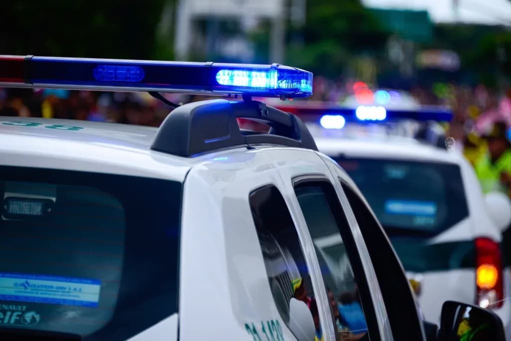 Mașini de poliție albe, cu luminile albastre pornite, într-un cadru urban. (Foto ilustrativă: necunoscut / CC0 1.0, Openverse)