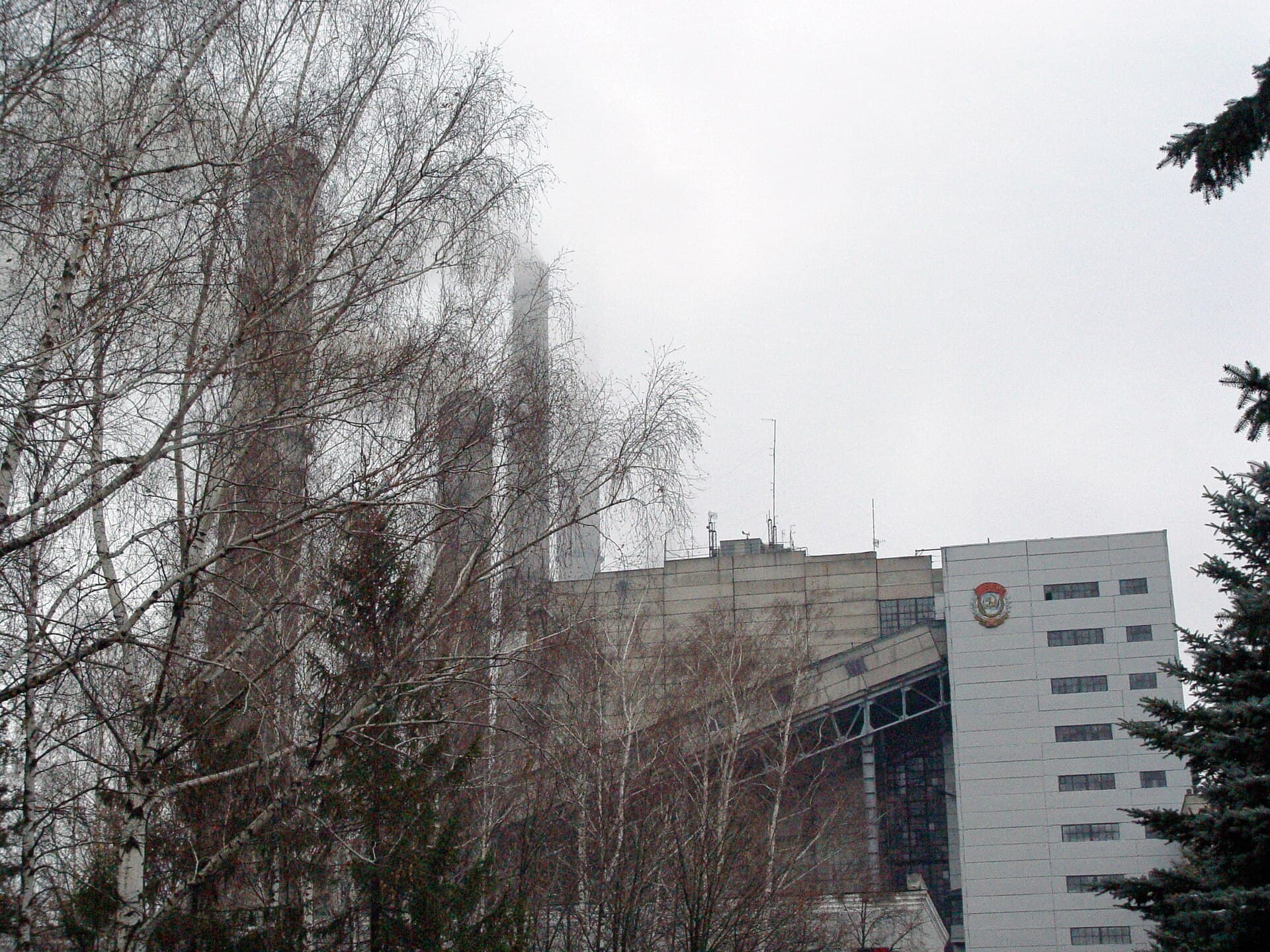 O instalație industrială energetică, cu clădire tehnică și coșuri înalte, văzută printre copaci. (Foto: Serhii Bobok If you have any questions please contact with me . Other photos see / CC BY-SA 4.0, Wikimedia Commons)