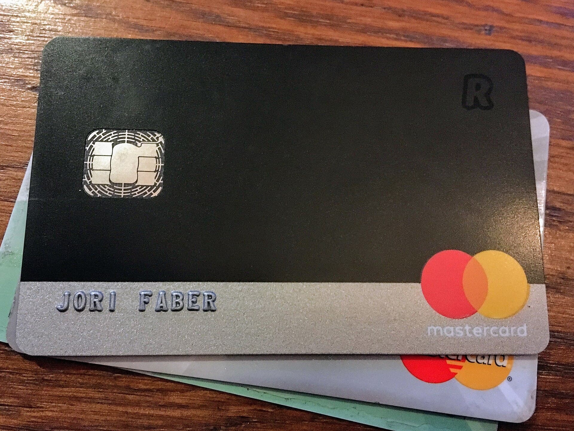 Un card Revolut Mastercard, negru, fotografiat deasupra altor carduri, cu numele „Jori Faber” vizibil. (Foto: JFD~nlwiki / CC BY-SA 4.0, Wikimedia Commons)