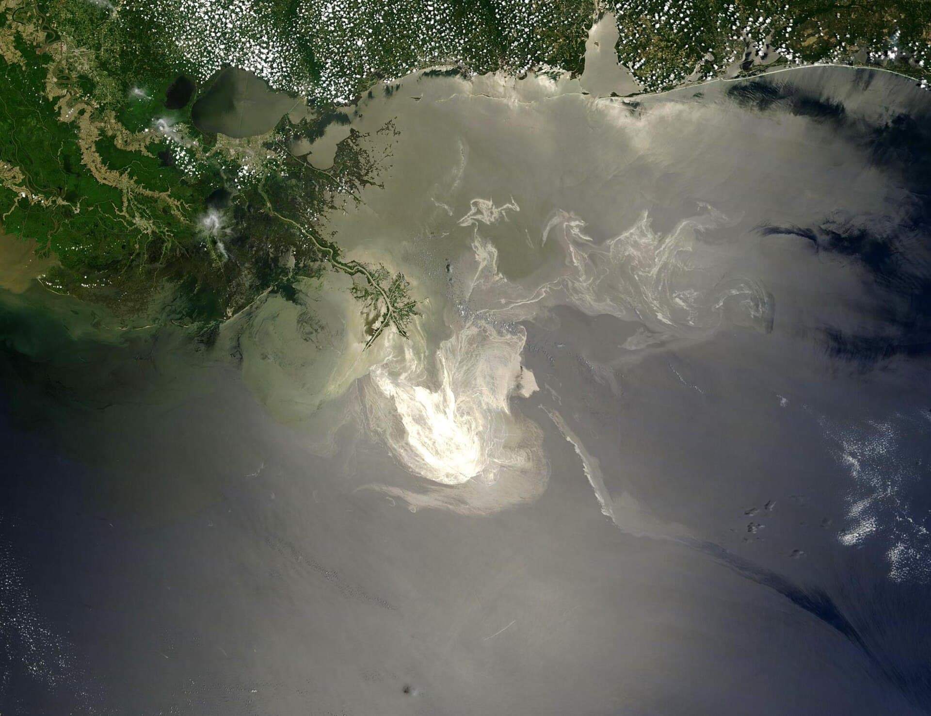 Imagine satelitară a unei pete mari de petrol care se extinde pe suprafața mării, în apropierea unei zone de coastă. (Foto de arhivă: NASA / GSFC , MODIS Rapid Response / Public domain, Wikimedia Commons)