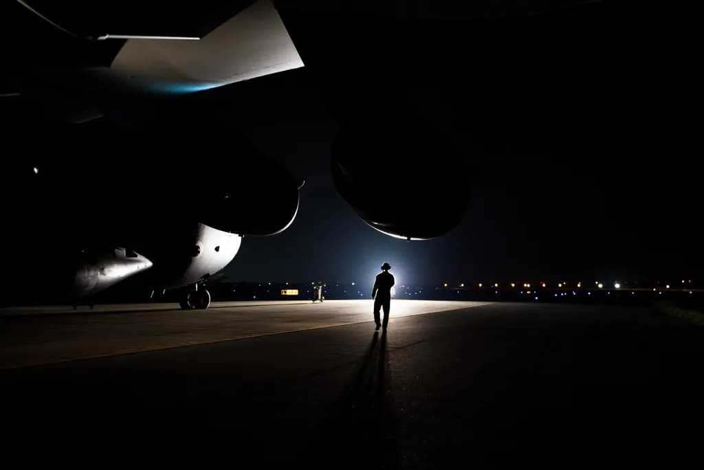 Un avion militar aflat noaptea pe o pistă, cu o persoană în siluetă în fața aeronavei. (Foto ilustrativă: U.S. Forest Service (source) / CC0 1.0, Openverse)