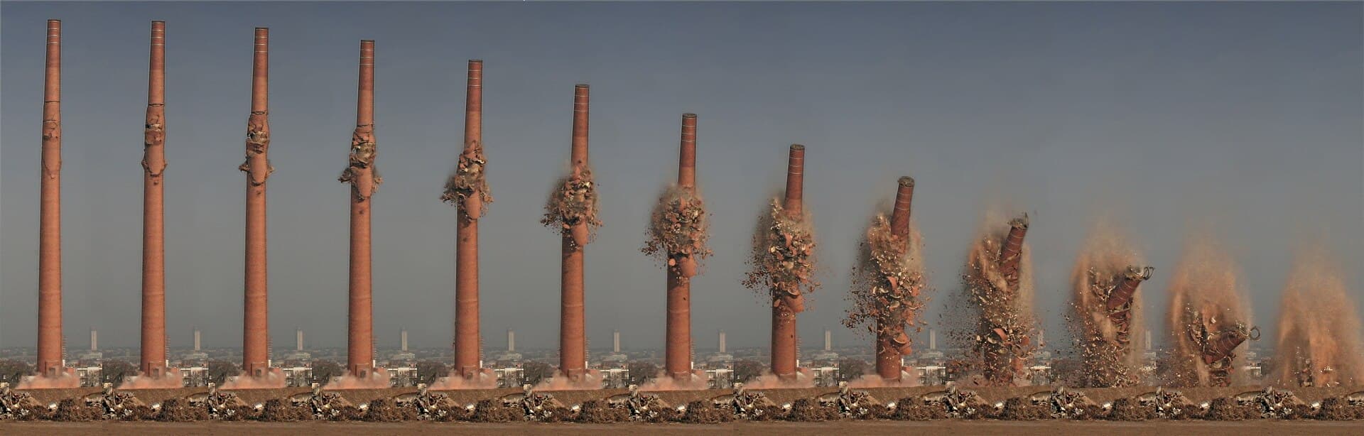Secvență fotografică a demolării controlate a unor coșuri industriale, cu explozii și nori de praf. (Foto de arhivă: Heptagon / CC BY-SA 3.0, Wikimedia Commons)