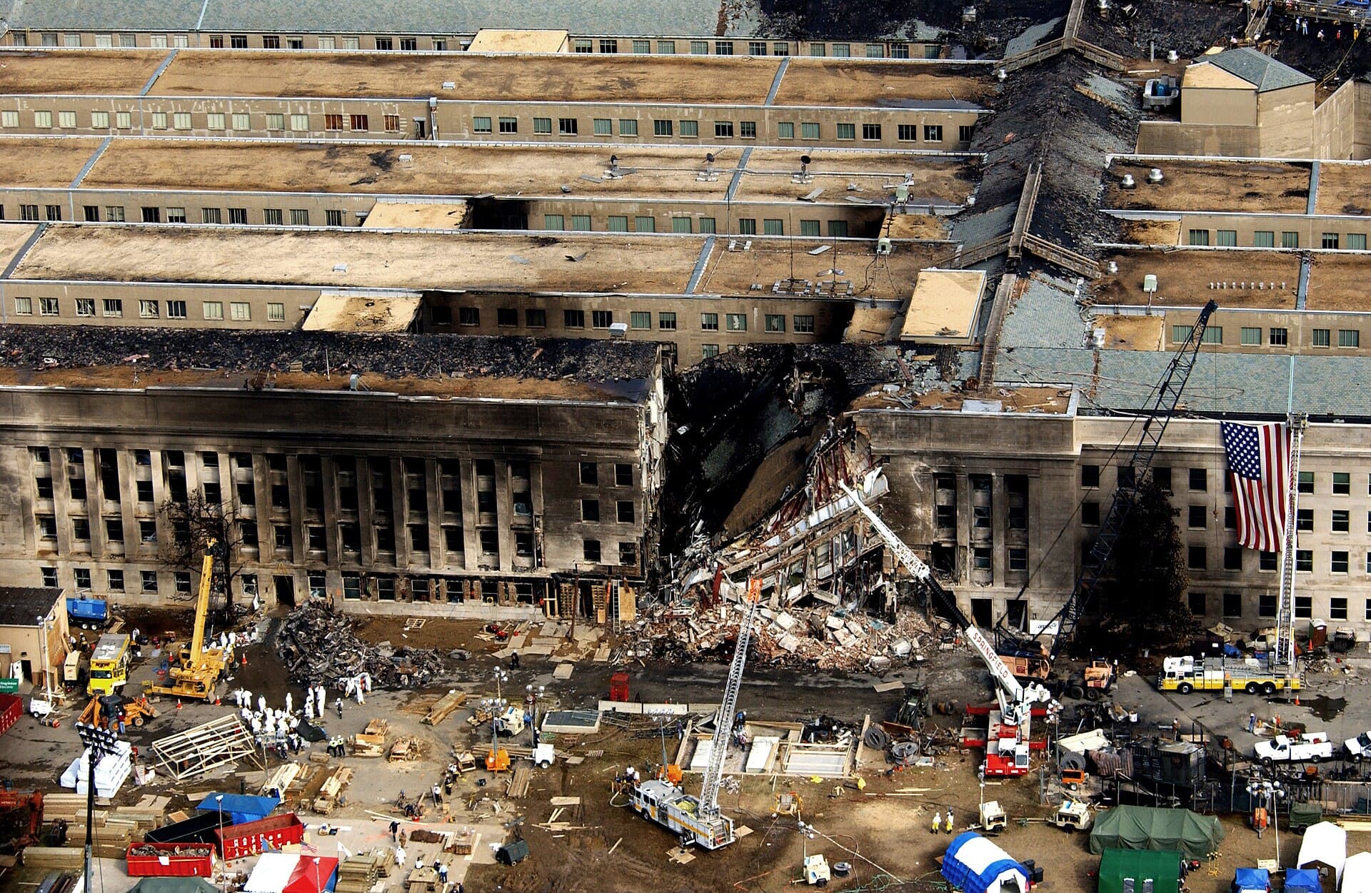 Clădirea Pentagonului, fotografiată după atacul din 11 septembrie, cu zona avariată și echipe de intervenție în jur. (Foto: TSGT CEDRIC H. RUDISILL, USAF / Public domain, Wikimedia Commons)