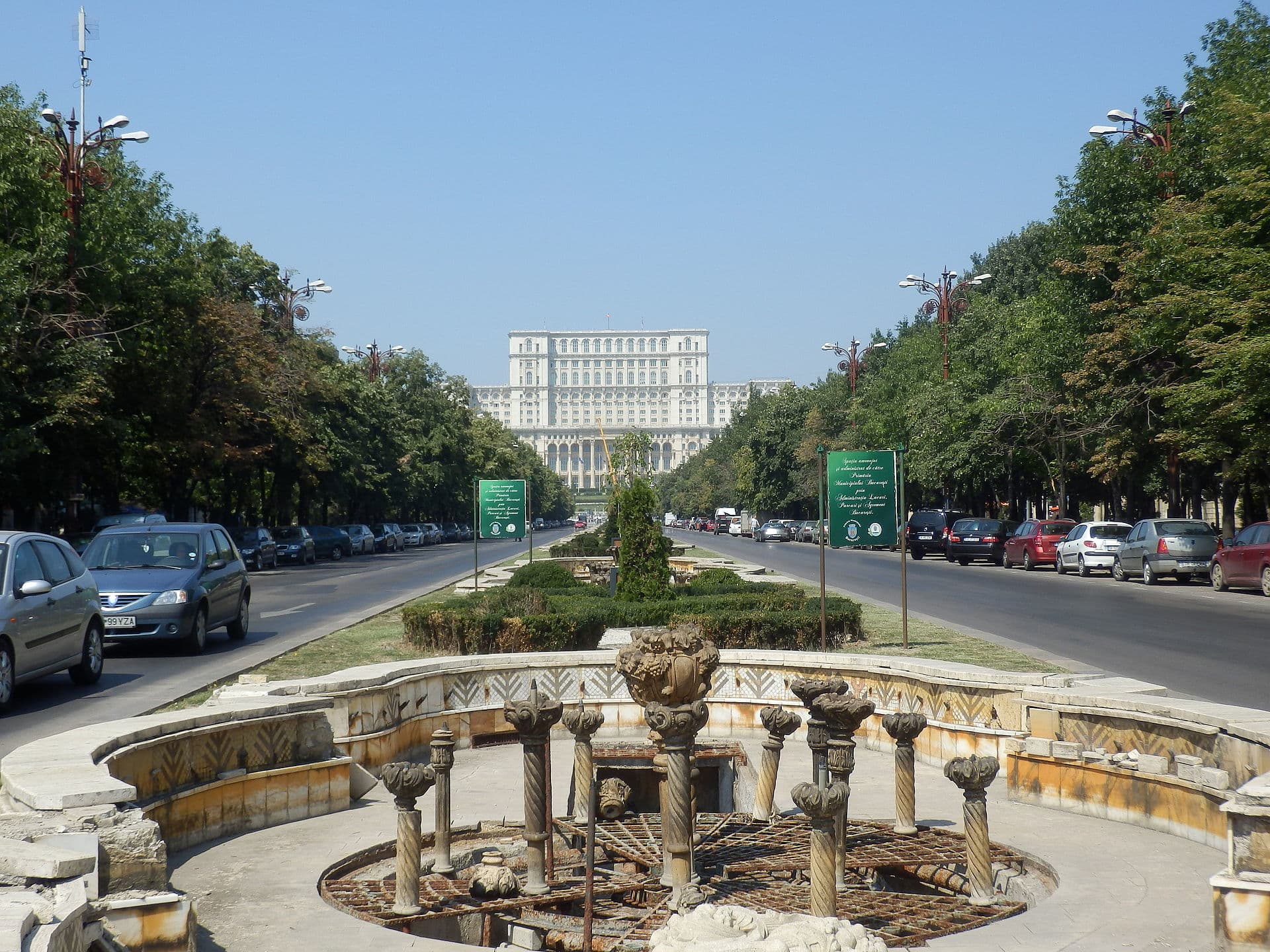 Bulevard din București, cu o fântână în prim-plan și o clădire guvernamentală în fundal. (Foto: Stefan Jurca from Munich, Germany / CC BY-SA 2.0, Wikimedia Commons)