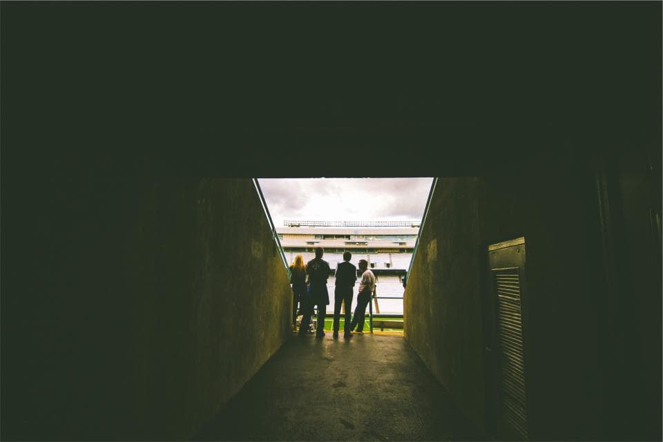 Un grup de persoane, probabil jucători, văzuți din spate într-un tunel care duce spre un teren de sport. (Foto ilustrativă: Abigail Keenan / CC0 1.0, Openverse)