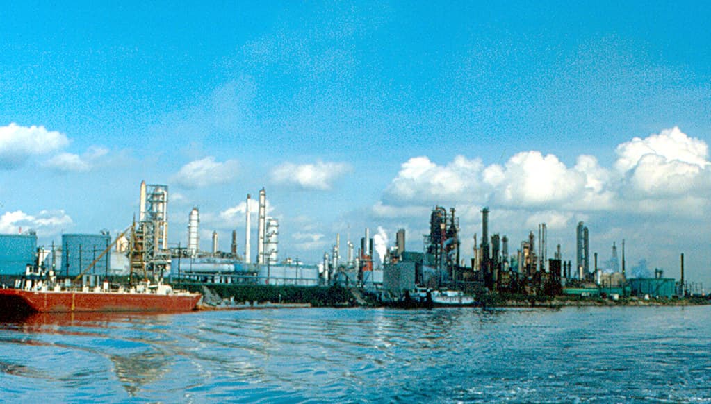 Complex industrial de rafinare, cu instalații petroliere și un vas pe apă, văzut de la distanță. (Foto de arhivă: roger4336 / BY-SA 2.0, Openverse)