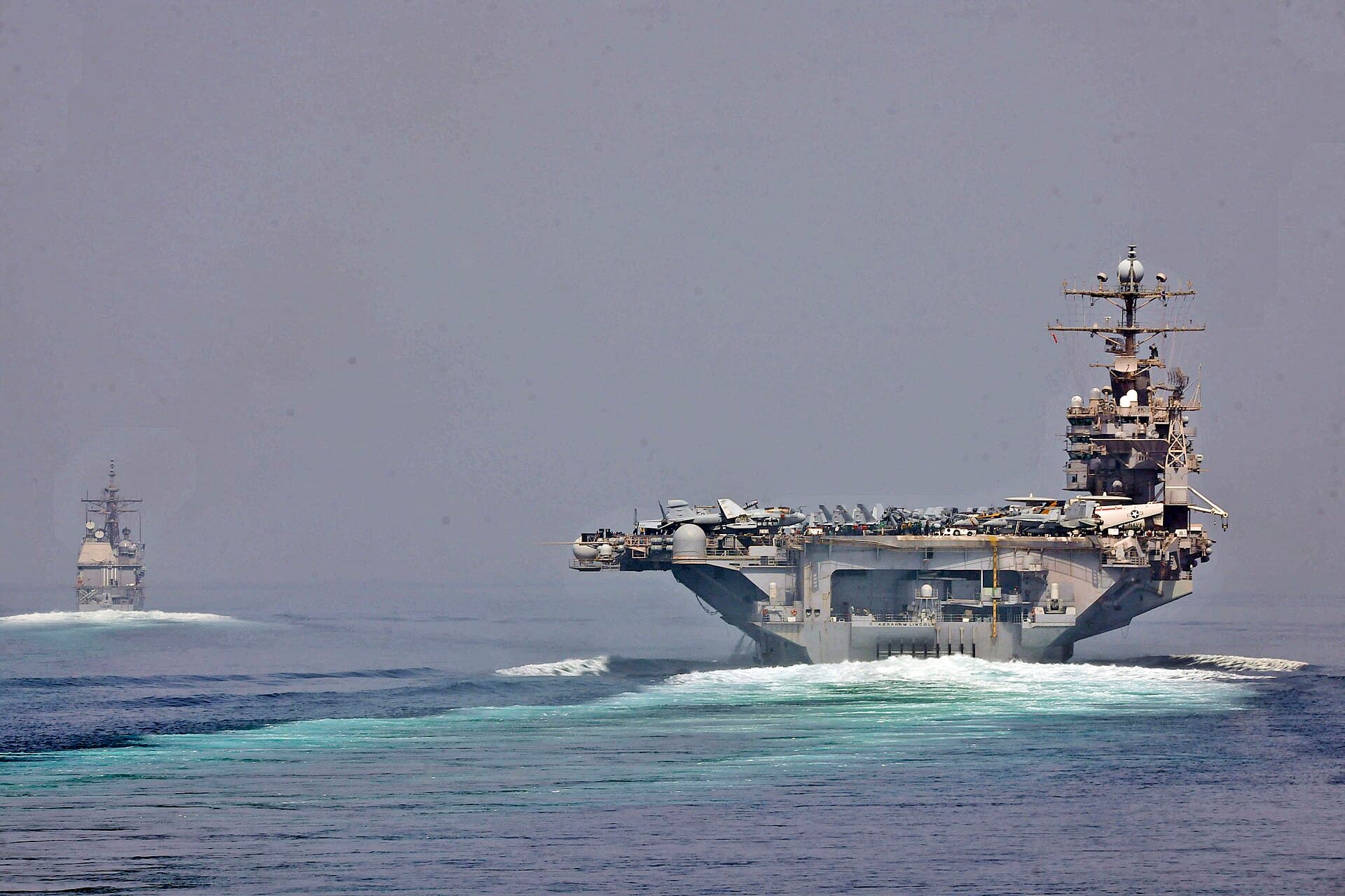 Două nave militare, inclusiv un portavion, navigând pe mare. (Foto: Official Navy Page from United States of America Alex R. Forster/U.S. Navy / Public domain, Wikimedia Commons)