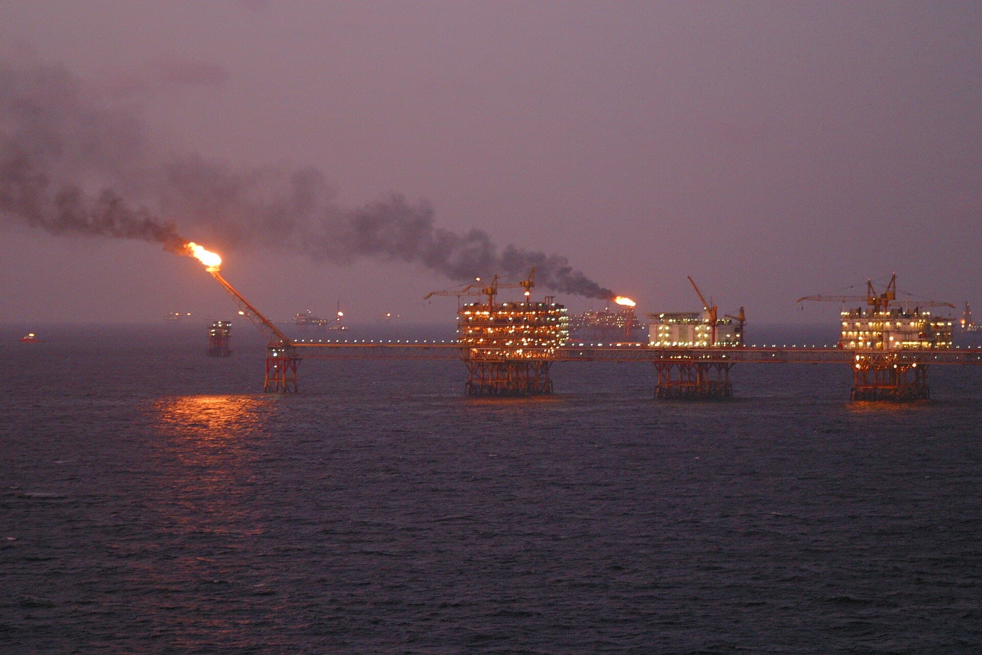 Platforme petroliere și instalații offshore pe mare, cu flăcări de gaze și fum. (Foto de arhivă: Genghiskhanviet / Public domain, Wikimedia Commons)