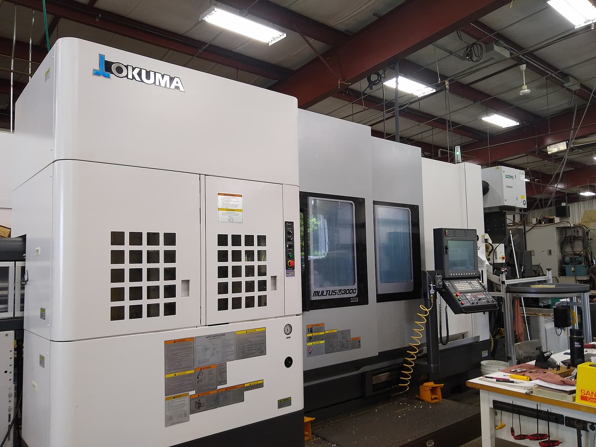Un utilaj industrial de prelucrare CNC, marca Okuma, într-un atelier sau într-o hală de producție. (Foto de arhivă: Whoisjohngalt / CC BY-SA 4.0, Wikimedia Commons)