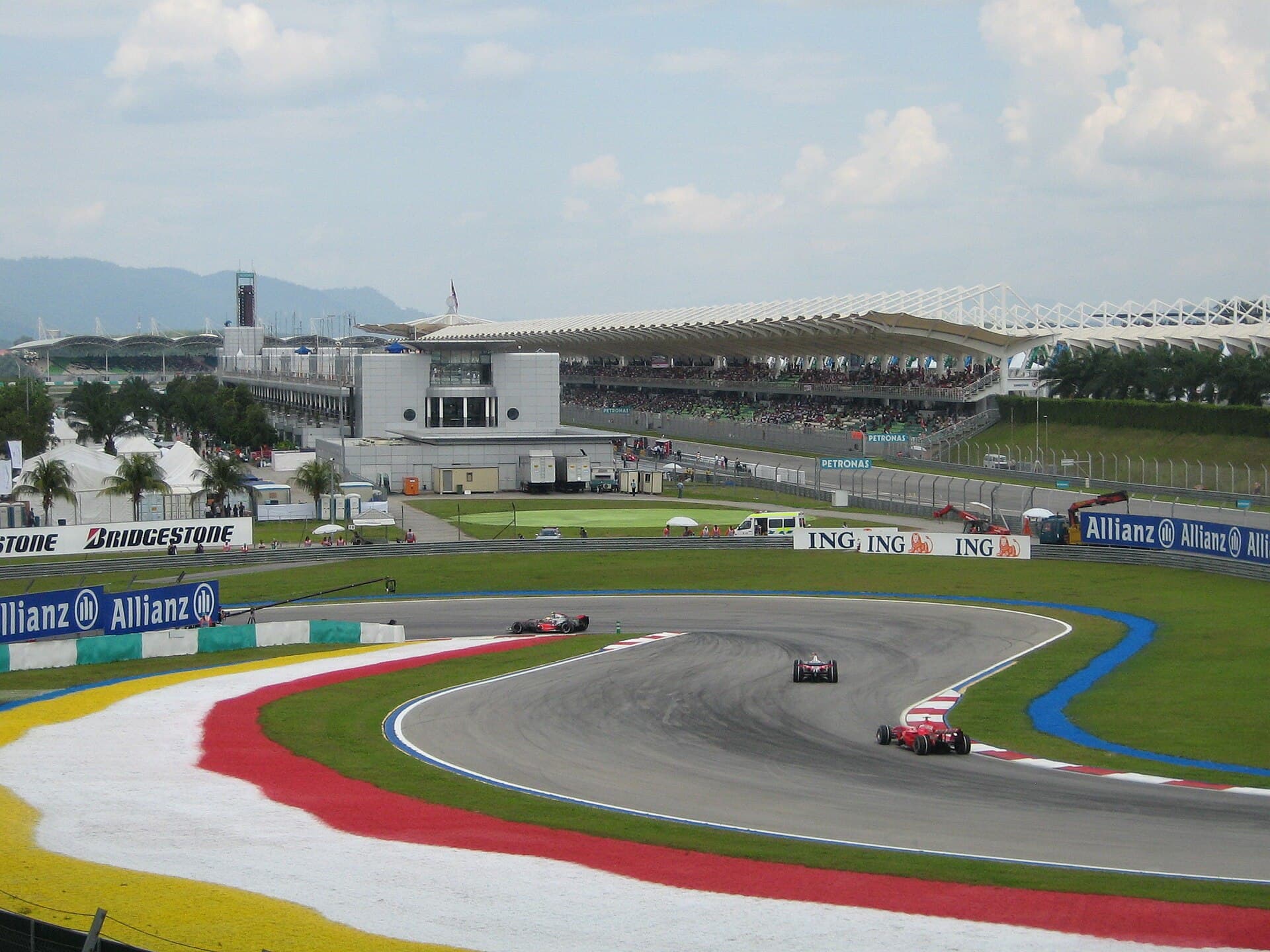 Circuitul internațional Sepang, cu mai multe mașini de curse pe pistă și tribunele în fundal. (Foto: Craig / Public domain, Wikimedia Commons)