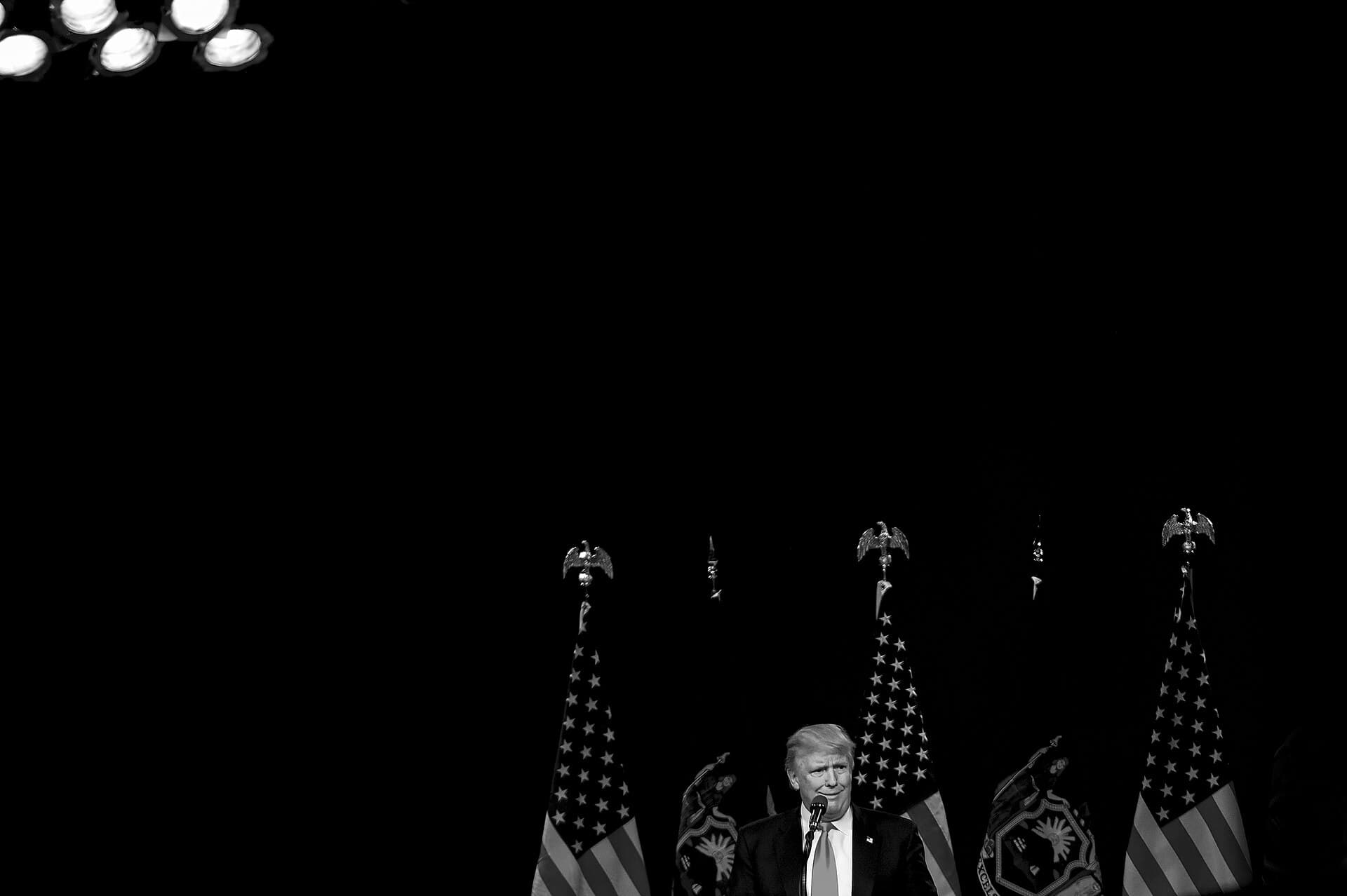 Donald Trump la un pupitru, într-o sală întunecată, flancat de steaguri ale Statelor Unite. (Foto: Staff Sgt. Kenny Holston / Public domain, Wikimedia Commons)