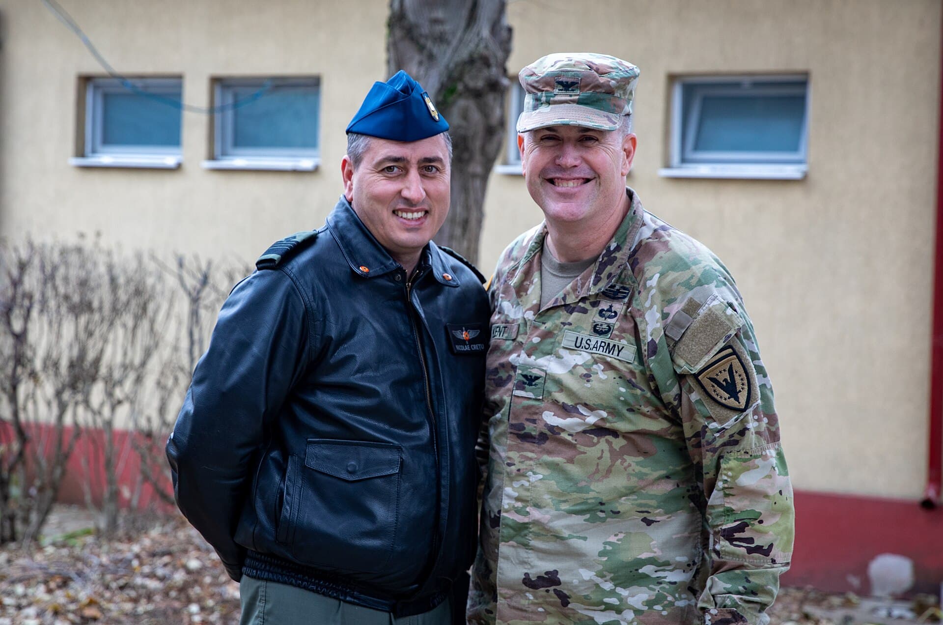 Un militar al armatei SUA și un militar român, fotografiați împreună în fața unei clădiri. (Foto: U.S. Army 1BCT-82ABN by Pfc. Aiden O'Marra / Public domain, Wikimedia Commons)