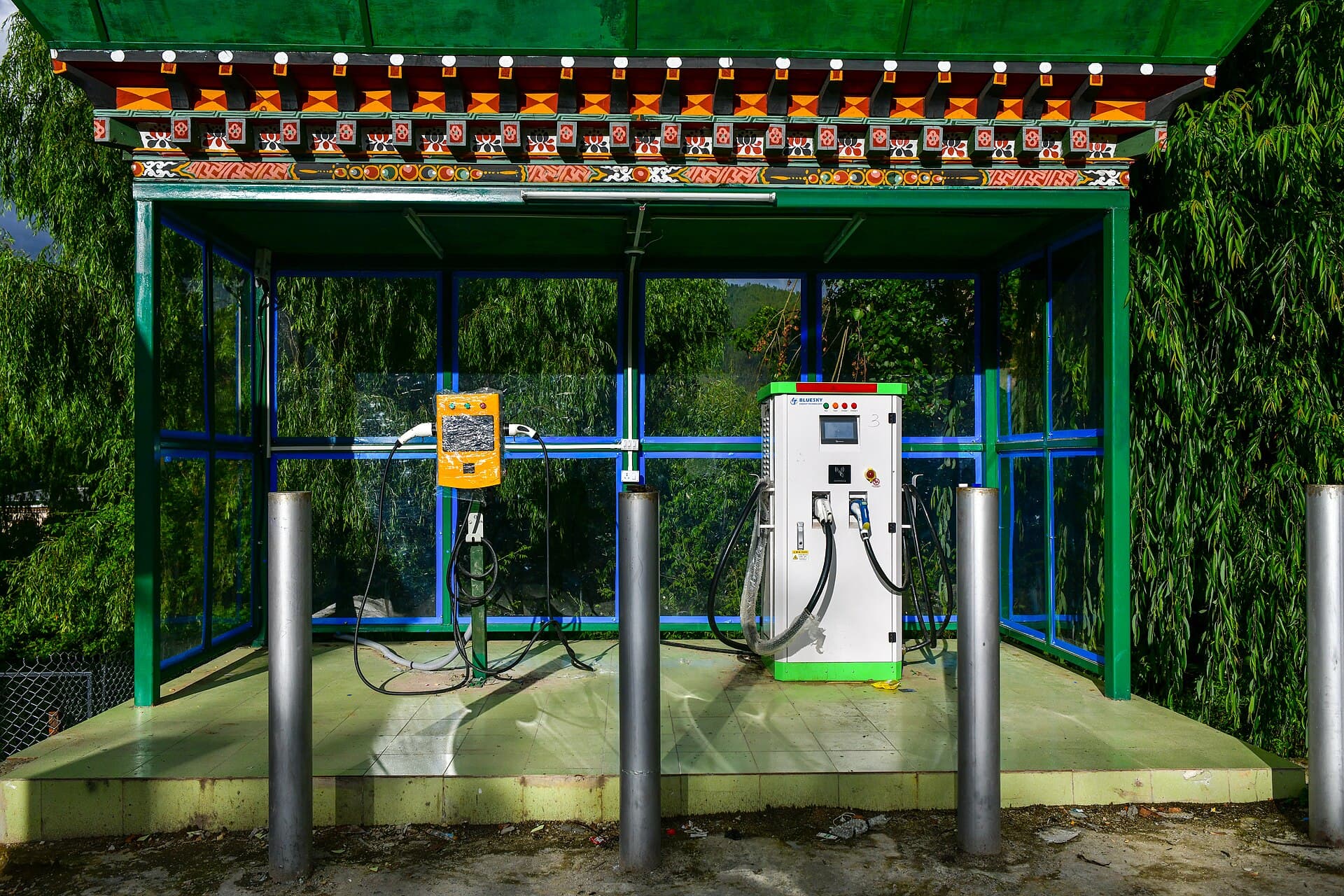 Stație de încărcare pentru vehicule electrice, cu două încărcătoare și cabluri, amplasată sub un acoperiș. (Foto de arhivă: Christopher J. Fynn / CC BY-SA 4.0, Wikimedia Commons)